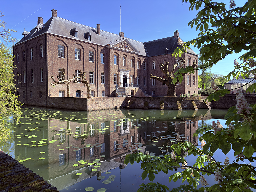Kasteel weerspiegeld in de slotgracht, omgeven door groen